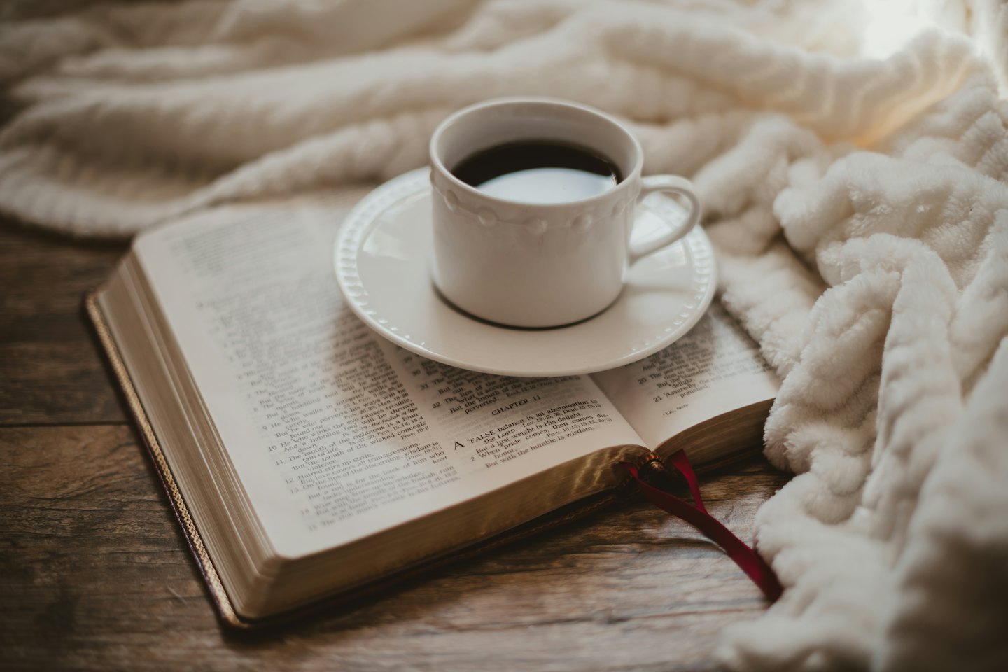 Schwarzer Kaffee in einer weißen Tasse steht auf einem offenen Buch.