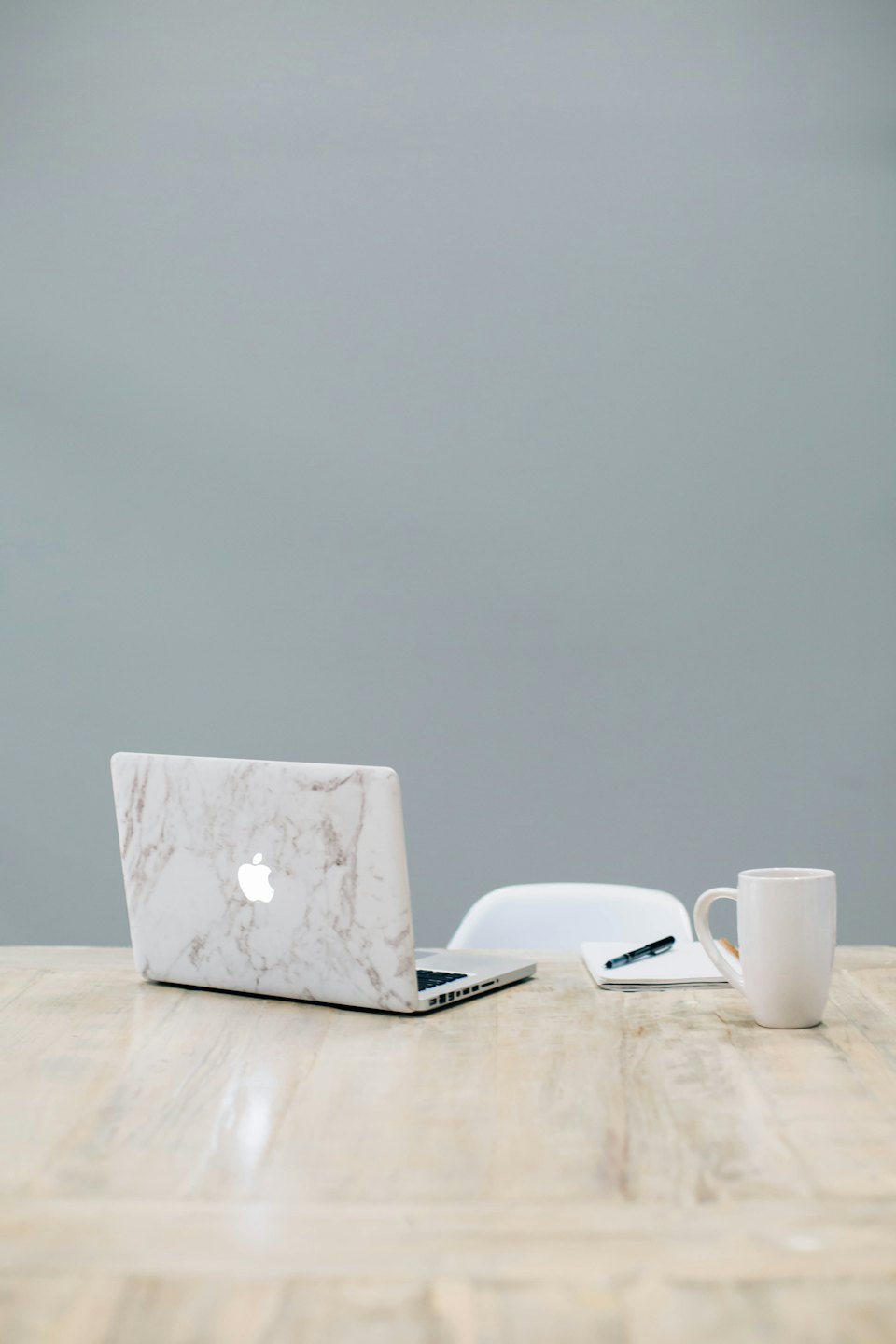 Laptop, Notizbuch und Kaffeetasse auf einem Holztisch.